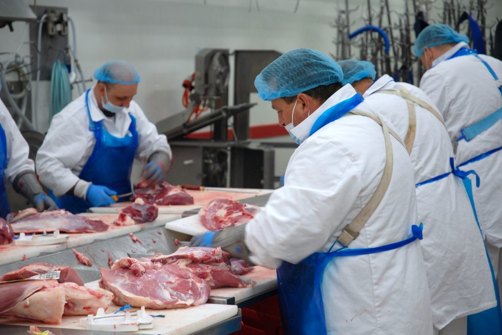 Aufnahme von vier Fleischern bei der Arbeit am Fleischtisch im Zerlegebetrieb in Weiz der Gassner GmbH